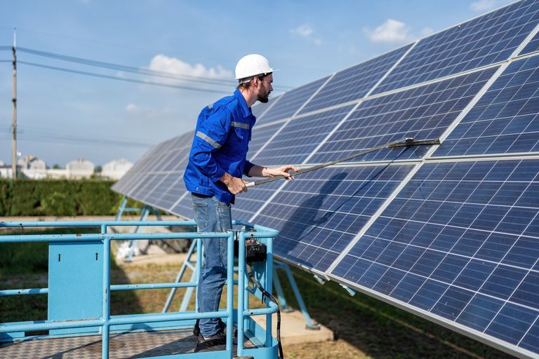 Service engineer use a mop cleaning solar panel for good performance service power generation