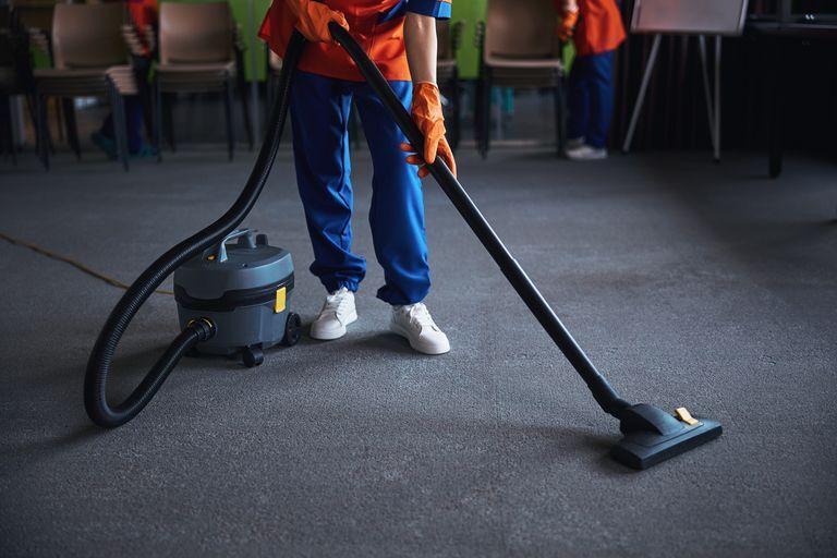 Cleaning lady using a canister vacuum cleaner